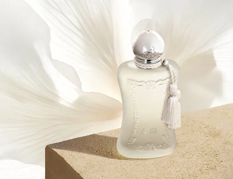 Her ses en parfums de marly lys parfume stående på et stenbord og med et hvidt blomsterblad i baggrunden.