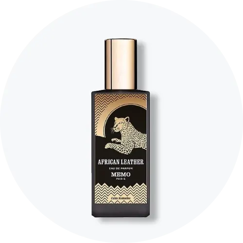 Her ses et billede af en parfumeflakon fra Memo Paris placeret centralt mod en lys, rund baggrund. På flakonen står teksten “AFRICAN LEATHER EAU DE PARFUM MEMO PARIS”. Flakonen er sort med guldfarvede detaljer og illustration af et dyr på fronten.