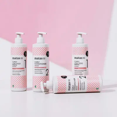 Her ses en hvid og lyserød baggrund med fire lyserøde og hvide Curly produkter fra Matas Striber. 