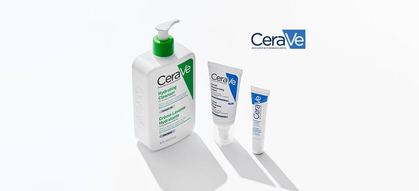 Tre hudplejeprodukter fra CeraVe står på en lys, ensfarvet baggrund med bløde skygger. Til venstre ses en stor, hvid pumpeflaske med grøn pumpe og grøn label med teksten “Hydrating Cleanser”. Til højre for den står to mindre, hvide tuber med blå detaljer og CeraVe-logoet. Produkterne er placeret med lidt afstand imellem, så hver enkelt fremstår tydeligt. Øverst til højre i billedet ses CeraVe-logoet. Udtrykket er rent, klinisk og enkelt med fokus på produkterne.