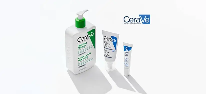 Tre hudplejeprodukter fra CeraVe står på en lys, ensfarvet baggrund med bløde skygger. Til venstre ses en stor, hvid pumpeflaske med grøn pumpe og grøn label med teksten “Hydrating Cleanser”. Til højre for den står to mindre, hvide tuber med blå detaljer og CeraVe-logoet. Produkterne er placeret med lidt afstand imellem, så hver enkelt fremstår tydeligt. Øverst til højre i billedet ses CeraVe-logoet. Udtrykket er rent, klinisk og enkelt med fokus på produkterne.