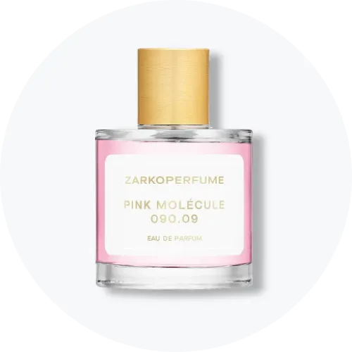 Her ses Zarkoperfume Pink Molécule 090.09 Eau de Parfum i en transparent, firkantet parfumeflakon med rosa indhold og guldfarvet låg. På forsiden ses en hvid etiket med produktnavnet i guldfarvet tekst. Flakonen står centralt mod en lys, rund baggrund.