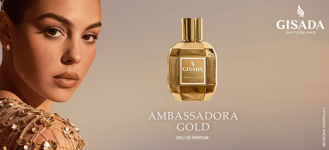 Her ses et billede af en person mod en varm beige baggrund ved siden af en parfumeflakon fra Gisada. På billedet står teksterne “GISADA SWITZERLAND” og “AMBASSADORA GOLD EAU DE PARFUM”. Personen er iført guldfarvede smykker, og parfumeflakonen har guldfarvede detaljer.
