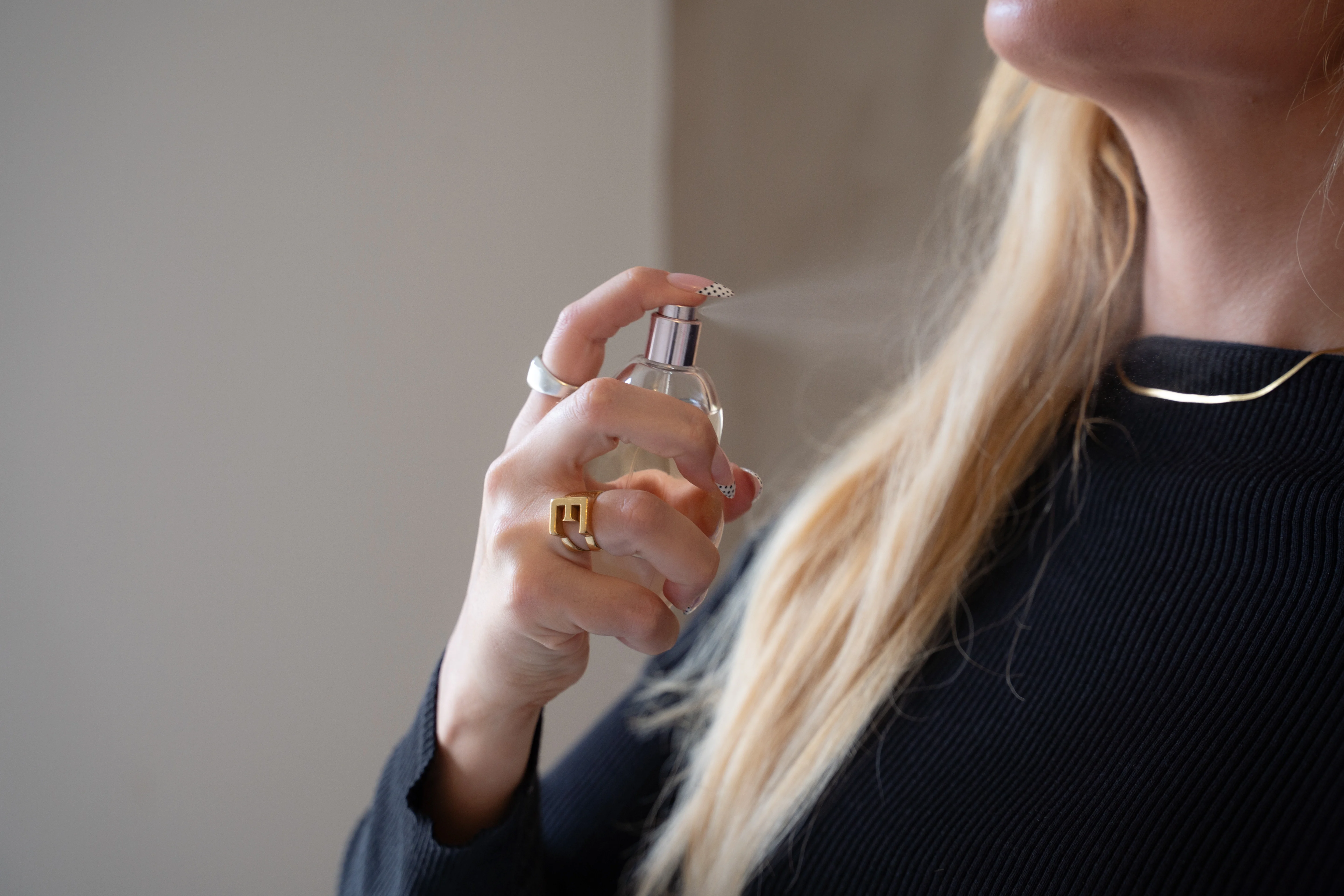 Kvinde, der sprøjter parfume på halsen