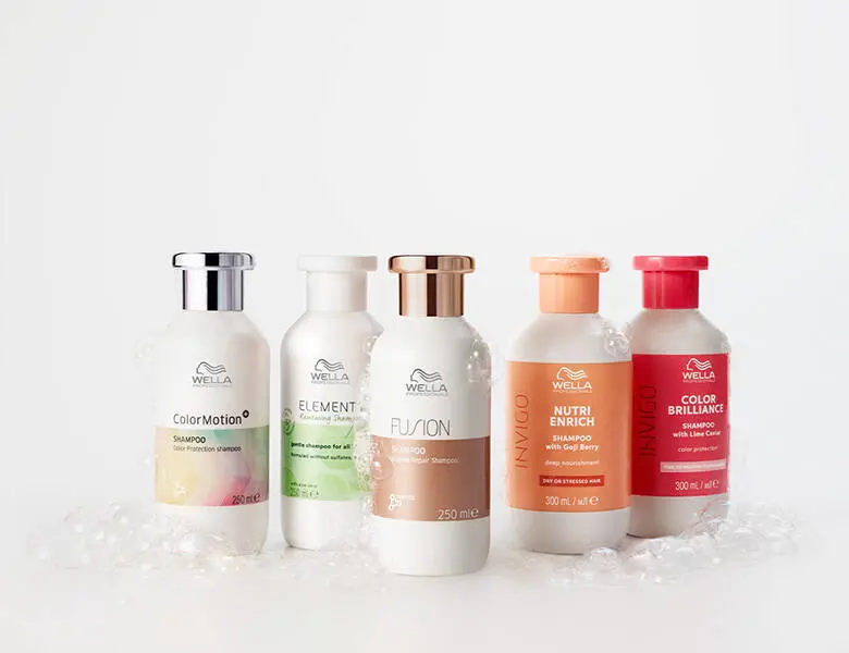 Her ses et billede med flere hårplejeprodukter fra Wella placeret side om side mod en lys baggrund. På produkterne står blandt andet “Color Motion+”, “Elements”, “Fusion”, “Nutri Enrich” og “Invigo”. Produkterne er i hvide, orange og pink nuancer.