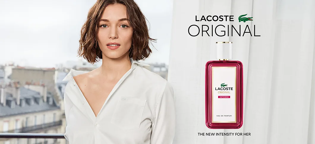 Her ses et kampagnebillede for Lacoste Original Intense Eau de Parfum. Til venstre ses en person i en hvid skjorte, og til højre ses den rosa parfumeflakon sammen med teksten “Lacoste Original” og “The New Intensity for Her”.