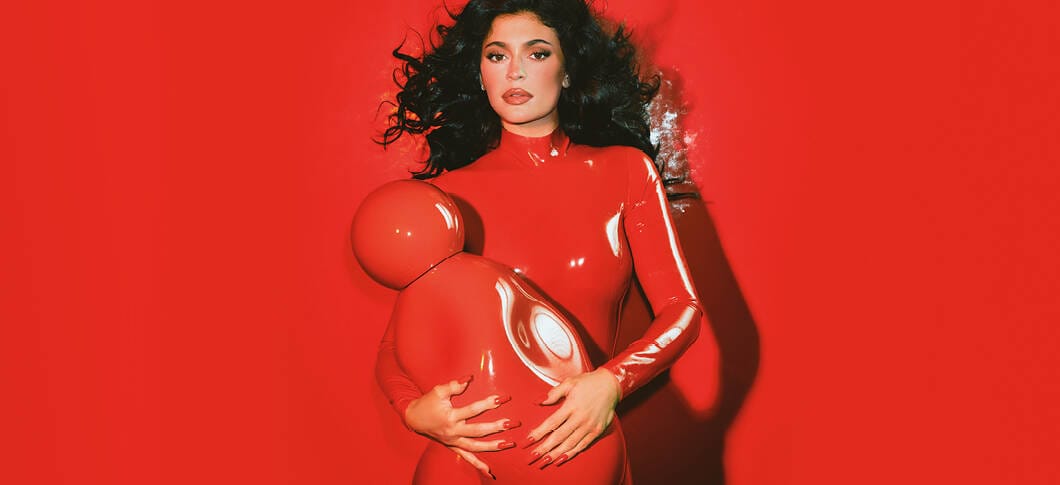 Her ses et billede af Kylie Jenner i rødt tøj, der holder en stor "Cosmic Intense" parfume foran sig. Baggrunden er også rød.