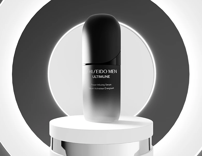 Her ses et billede af et hudplejeprodukt fra Shiseido Men placeret på et podium mod en mørk baggrund med cirkulært lys. På produktet står teksten “SHISEIDO MEN ULTIMUNE Power Infusing Serum”.