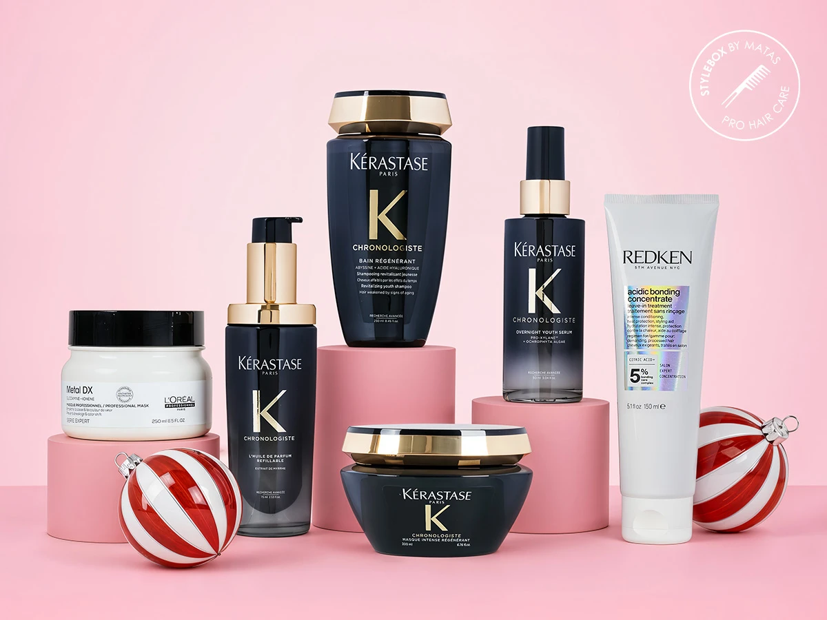 Et udvalg af hårplejeprodukter fra Kérastase, L'Oréal og Redken, arrangeret med røde og hvide julekugler.
