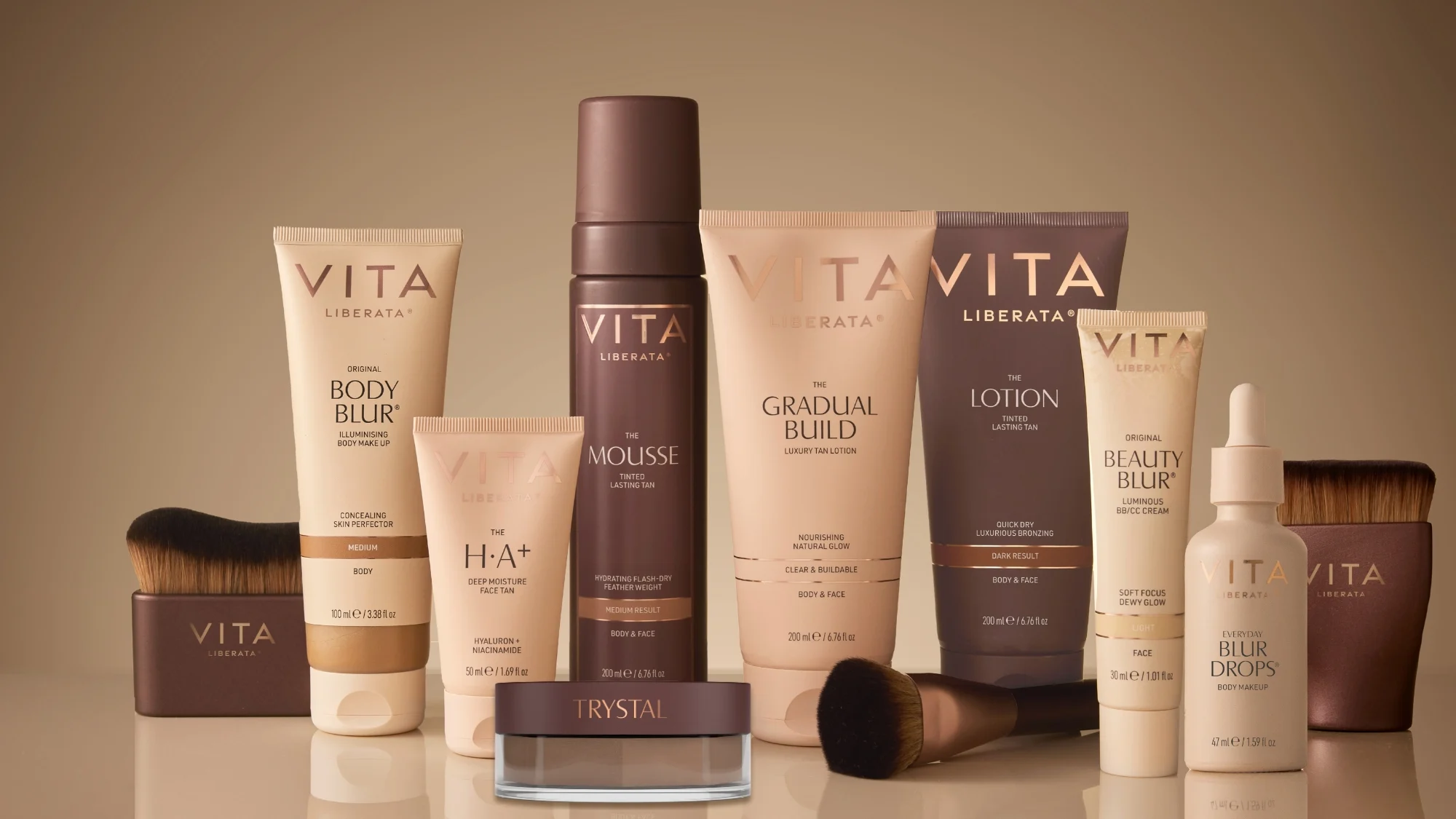Her ses Vita Liberata selvbrunerprodukter og makeup i beige og brune nuancer sammen med makeupbørster på en beige baggrund.