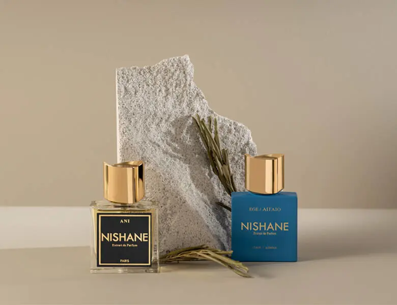 Her ses to NISHANE parfumer foran en sten. Baggrunden er beige.