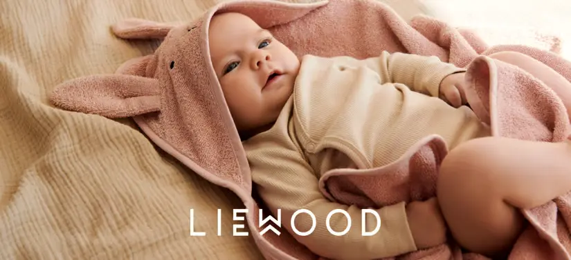 Her ses en liggende baby med en badekåbe på. Foran ses et hvidt logo. 