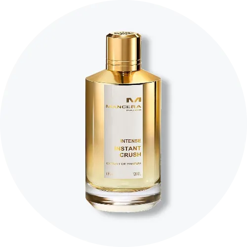 Her ses et billede af en parfumeflakon fra Mancera placeret centralt mod en lys, rund baggrund. På flakonen står teksten “MANCERA PARIS INTENSE INSTANT CRUSH”. Flakonen er i guldfarvet design med klart glas i bunden.