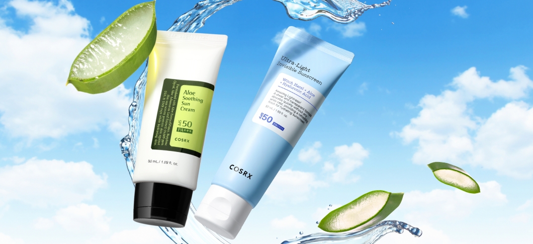 Her ses COSRX solcremer på en blå baggrund med vand og aloe vera.