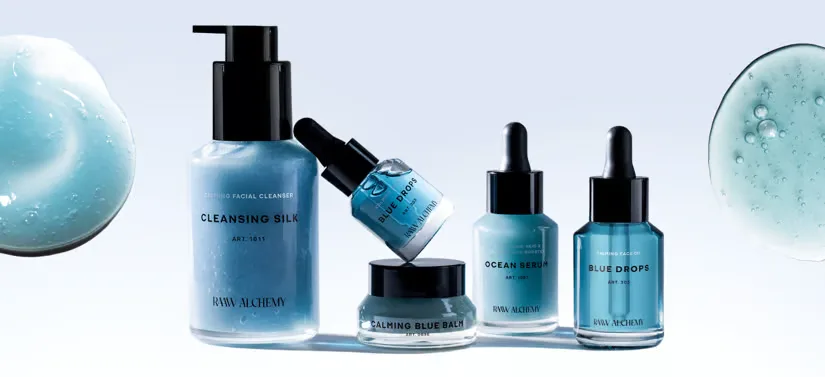 Her ses fem forskellige RAAW Alchemy produkter på en lyseblå baggrund.