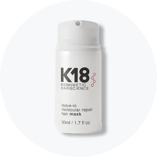 Her ses et billede af et hårplejeprodukt fra K18 placeret centralt mod en lys, rund baggrund. På produktet står teksten “K18 BIOMIMETIC HAIRSCIENCE leave-in molecular repair hair mask”. Flasken er i hvid emballage med pumpefunktion.