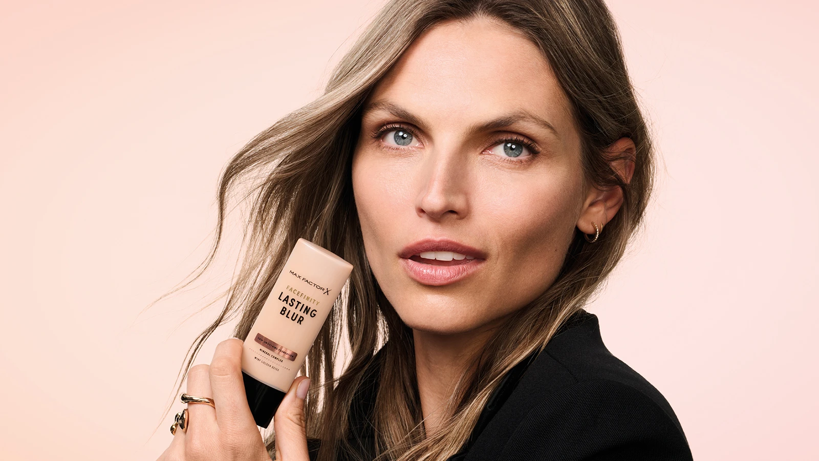 Model, der holder en lys beige tube med Max Factor Facefinity Lasting Blur foundation.