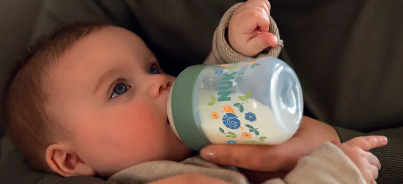 Her ses en baby, som får mælk fra en sutteflaske.