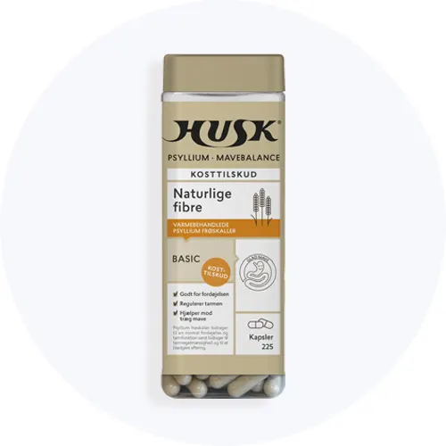 HUSK Psyllium Mavebalance kosttilskud med naturlige fibre i gennemsigtig beholder med beige låg og kapsler i bunden på lys grå baggrund.
