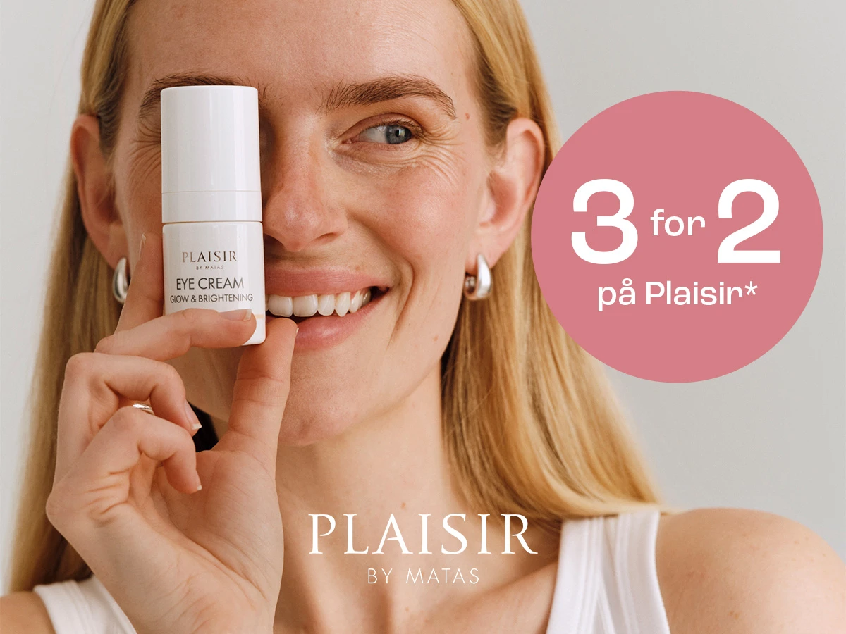 Kvinde smiler og holder Plaisir Eye Cream Glow & Brightening foran sit ansigt. Tilbud: 3 for 2 på Plaisir*. Brand: Plaisir by Matas.