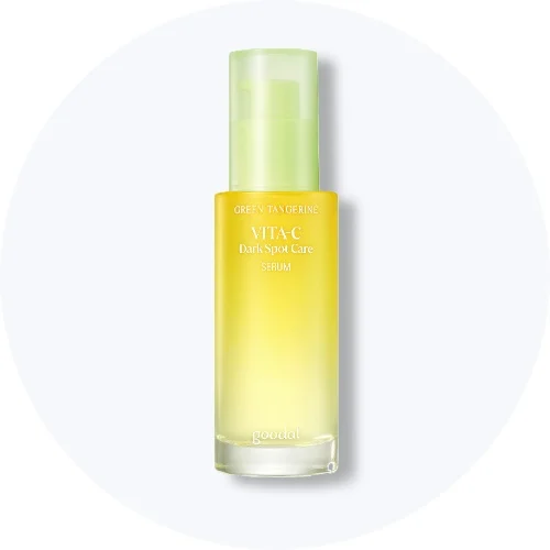 Her ses et Goodal Green Tangerine Vita-C Dark Spot Care Serum i en gul pumpeflaske med lysegrønt låg på en lys baggrund.