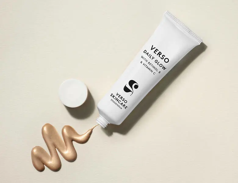 Her ses et hvidt Verso produkt, hvorfra der kommer en guldfarvet creme. Baggrunden er lys beige.
