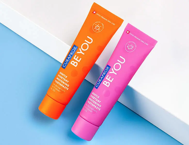 Her ses to tandpastaer - en i pink og en i orange. Baggrunden er halv blå og halv hvid.
