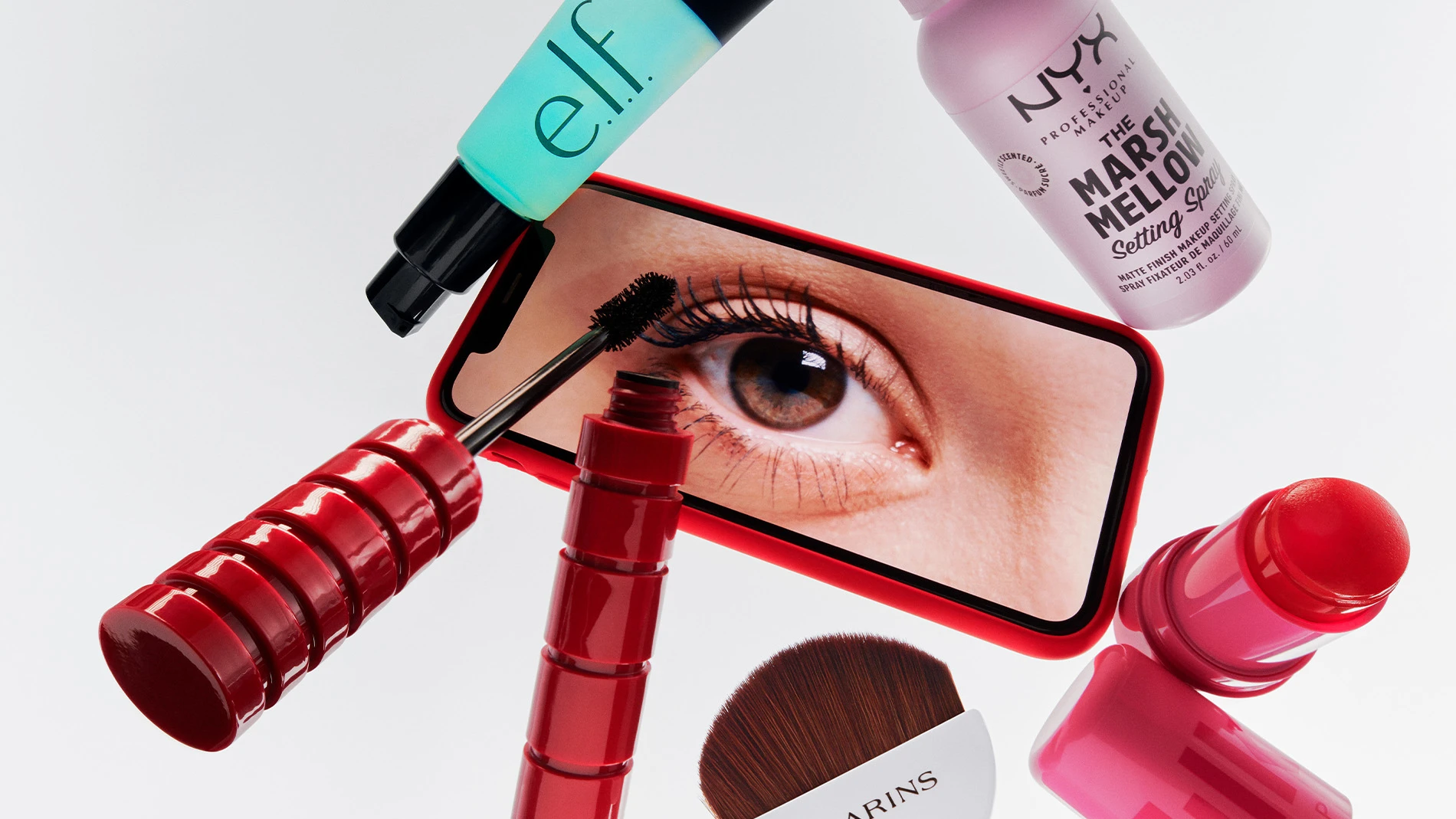 Sminkprodukter runt en mobiltelefon som visar ett öga med mascara.