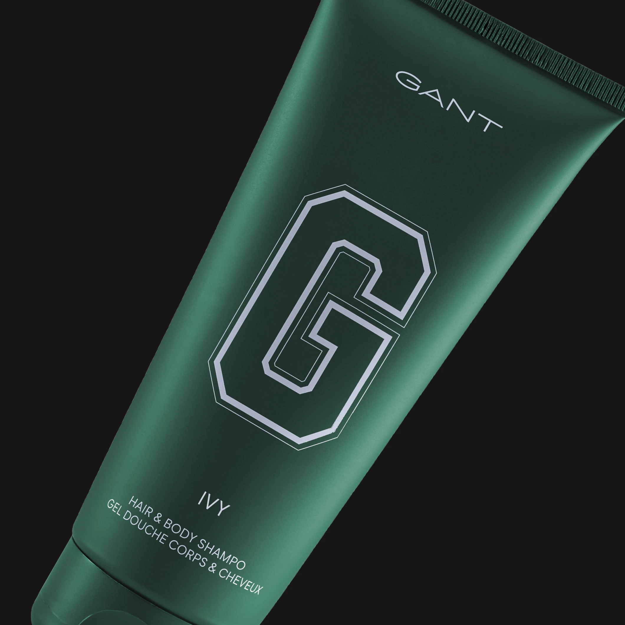 GANT Ivy Hair & Body Shampoo i mørkegrønn tube mot svart bakgrunn. Synlig tekst inkluderer “GANT”, “G”, “IVY” og “HAIR & BODY SHAMPOO”.