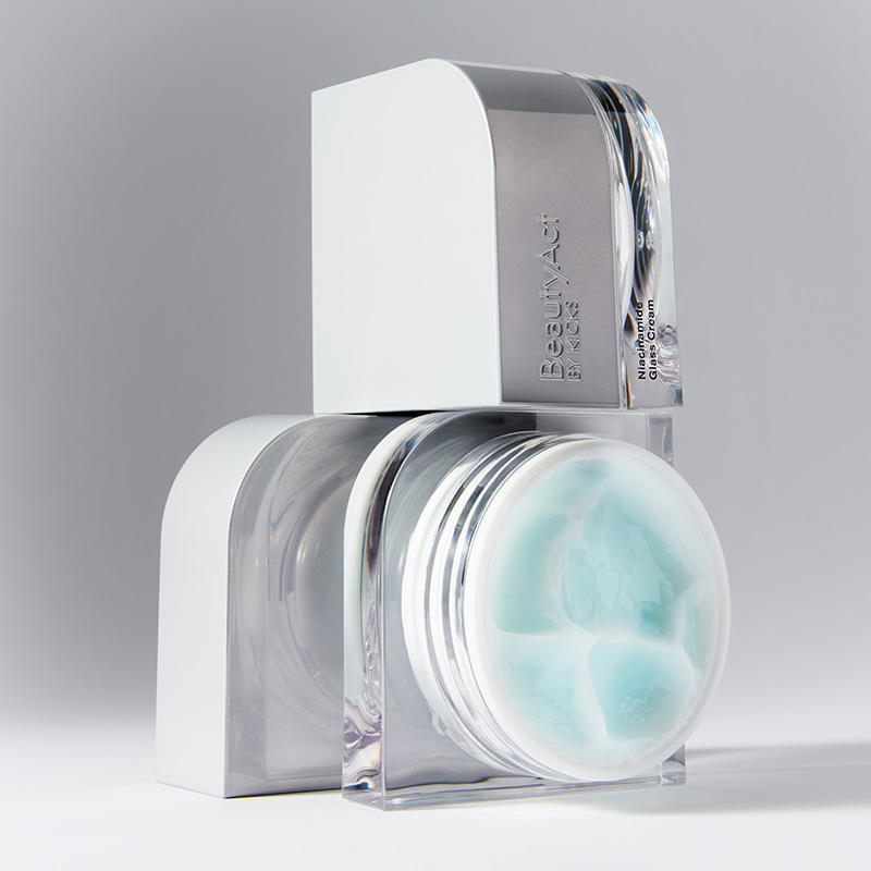 BeautyAct by KICKSin ihonhoitotuote Niasiiniamidi Glacier Cream. Pakkaus on valkoinen ja hopeanvärinen, ja sen läpinäkyvässä osassa on vaaleansininen voide. Tausta on vaaleanharmaa.
