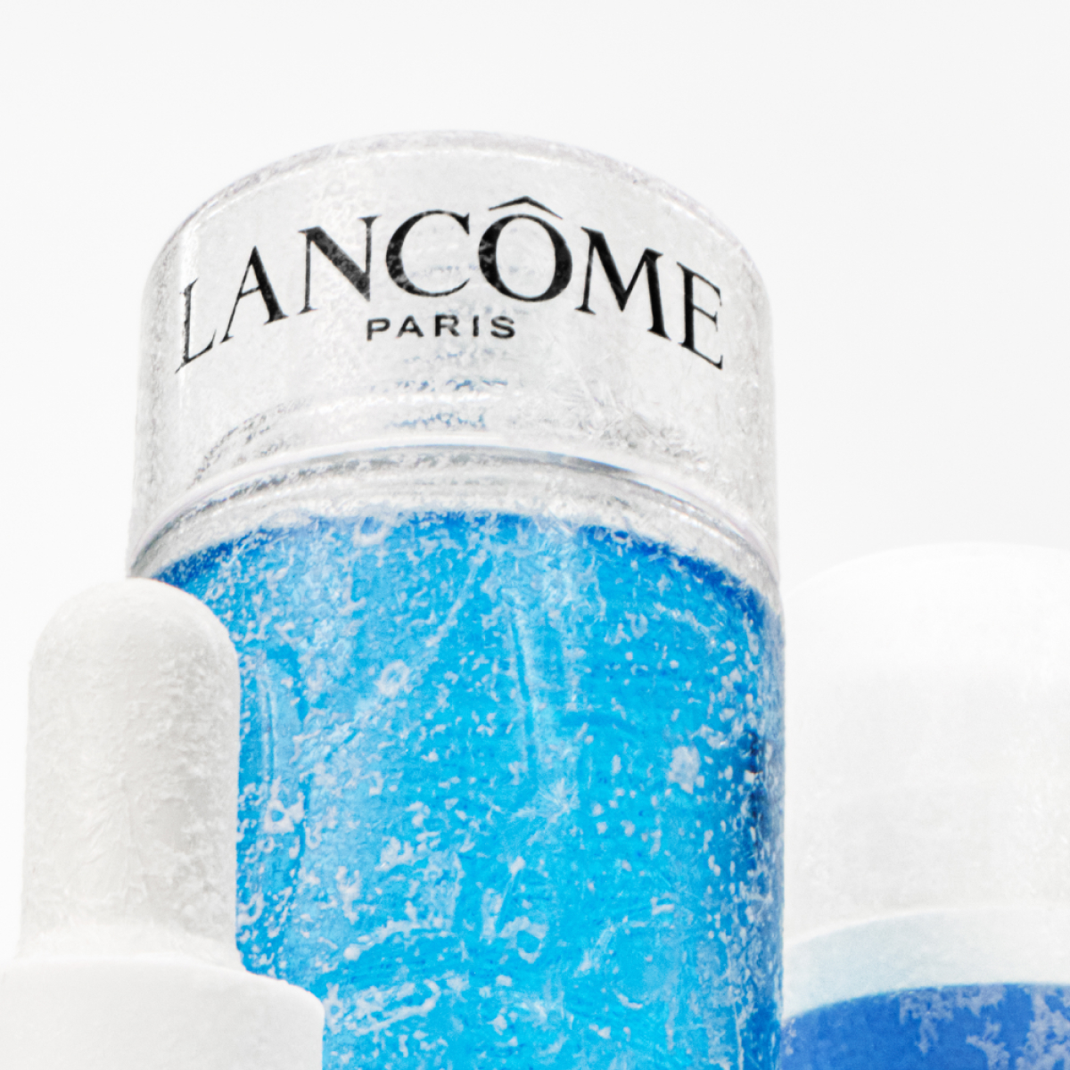 Produkt av Lancome underifrån tillsammans med andra produkter, mot en vit bakgrund