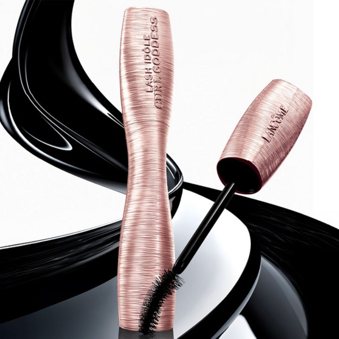 Nærbilde av en person som påfører Lancôme Lash Idôle Curl Goddess mascara på øvre vipper med synlig børste og produkttekst på hylsen.