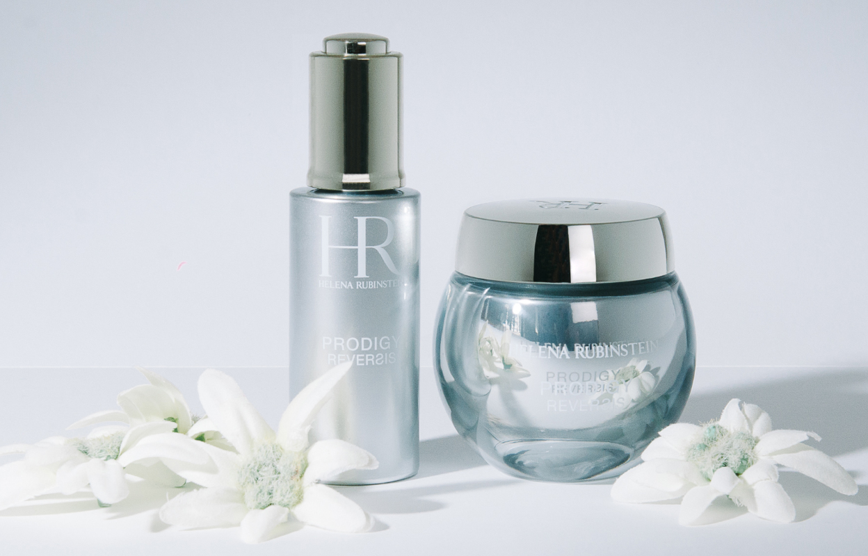 To Helena Rubinstein skjønnhetsprodukter, en flaske og en krukke, med hvite blomster plassert rundt.