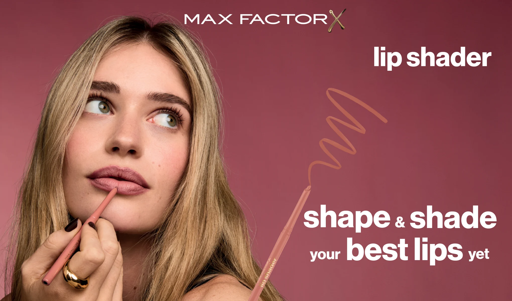 Kvinne former leppene med Max Factor Lip Shader-leppeblyant mot rosa bakgrunn.