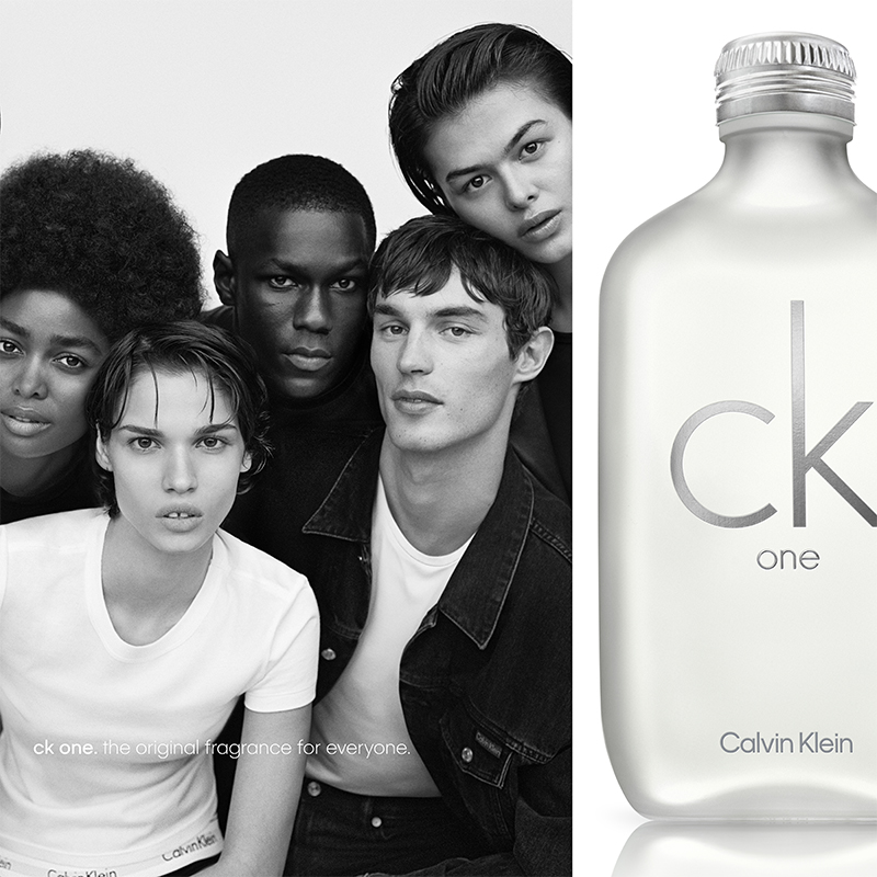 Till höger finns en Calvin Klein-parfymflaska märkt "ck one". Till vänster är en grupp människor klädda i vita t-shirts och jeansjackor. Texten "ck one. the original fragrance for everyone." syns längst ner.