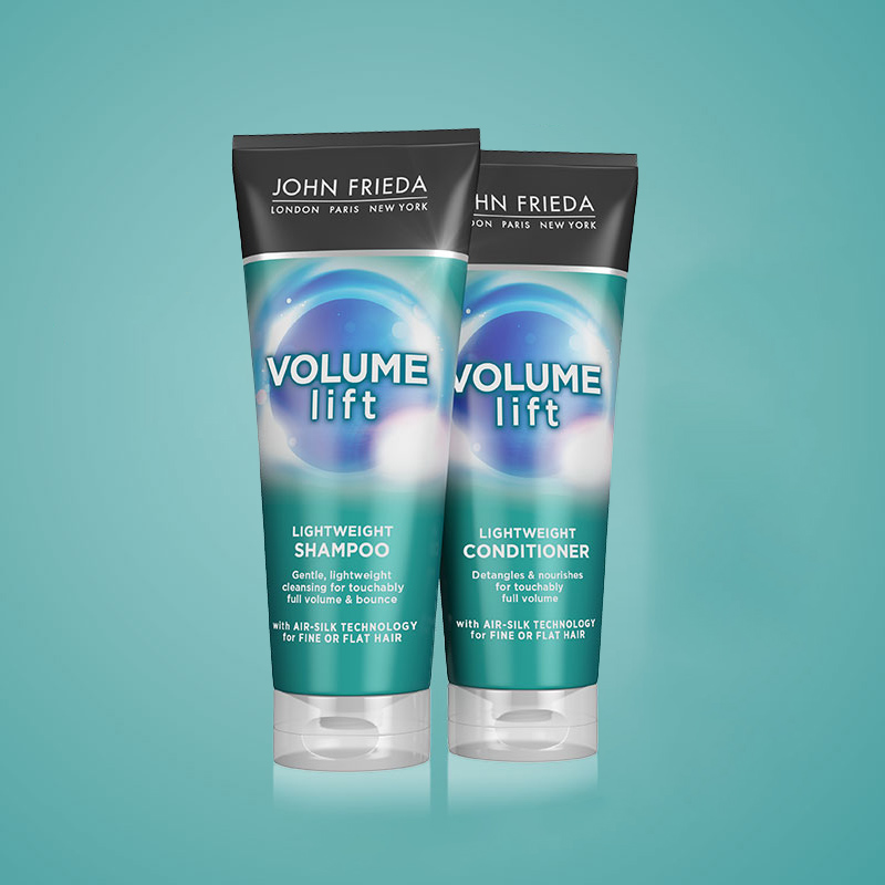 Kaksi hiustenhoitotuotetta John Friedalta, shampoo ja hoitoaine ”Volume Lift” -sarjasta. Tuotteissa on sininen ja vihreä kuvio, ja ne on sijoitettu vaaleansinistä taustaa vasten.