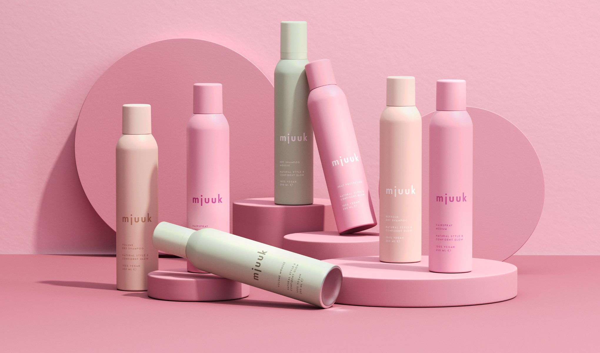 Flera rosa och pastellfärgade hårprodukter är stilfullt placerade på en rosa bakgrund. Produkterna är från märket "mjuuk" och inkluderar bland annat torrschampo och hårspray.