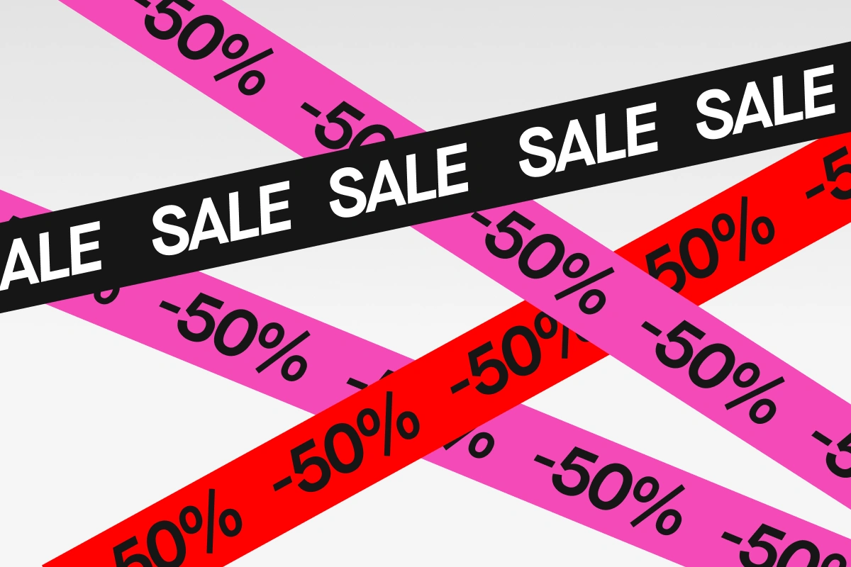 Graafinen SALE-banneri vaaleanharmaata taustaa vasten mustilla, pinkeillä ja punaisilla vinonauhoilla. Näkyvä teksti sisältää toistuvat “SALE” ja “50%”.