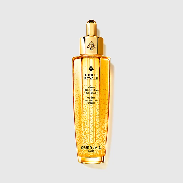 Guerlain Abeille Royale serum i en transparent gyllen flaske med pipette og synlige gyldne dråper. På flasken står “ABEILLE ROYALE”, “SERUM HUILE-EN-EAU JEUNESSE YOUTH WATERY OIL SERUM” og “GUERLAIN PARIS”.