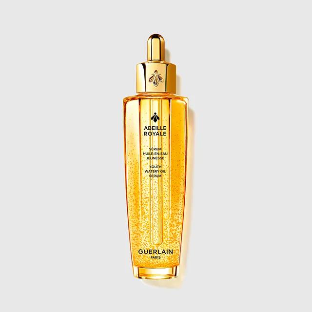 Guerlain Abeille Royale serum i en transparent gyllen flaske med pipette og synlige gyldne dråper. På flasken står “ABEILLE ROYALE”, “SERUM HUILE-EN-EAU JEUNESSE YOUTH WATERY OIL SERUM” og “GUERLAIN PARIS”.