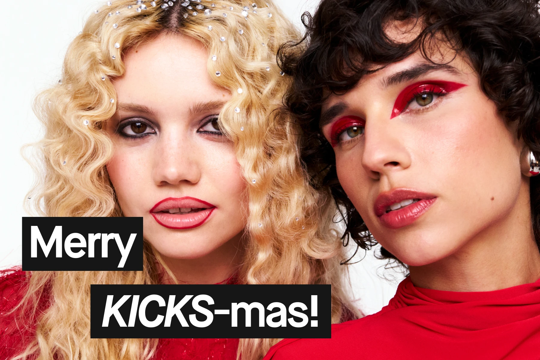 Två kvinnor står tillsammans mot en julröd bakgrund, Merry KICKS-MAS