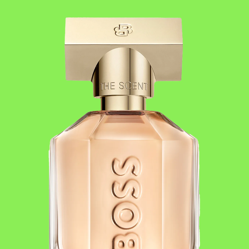 Parfymeflaske merket “BOSS THE SCENT” med gullfarget kork mot grønn bakgrunn.