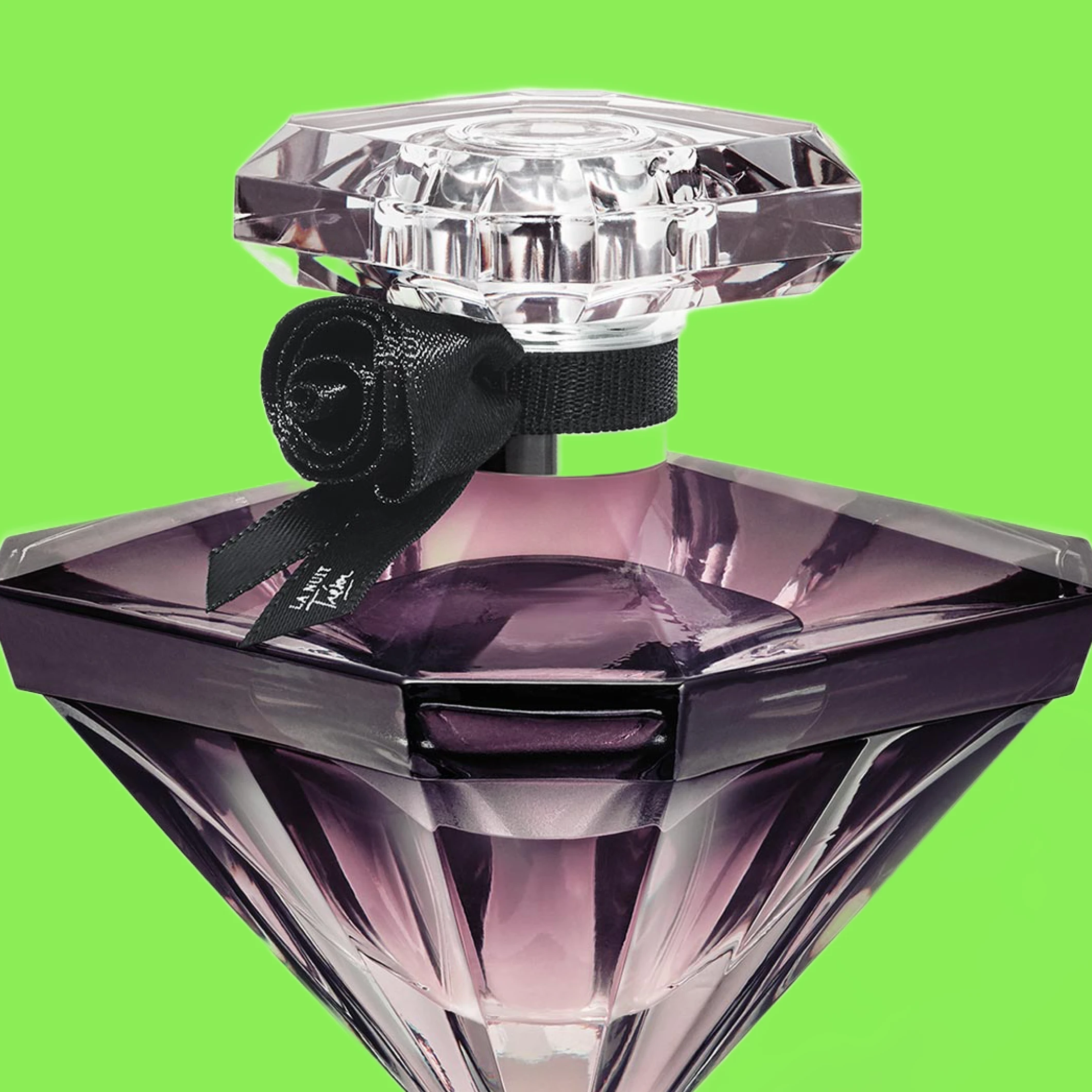 Lila diamantformad parfymflaska med svart rosett vid halsen mot grön bakgrund.