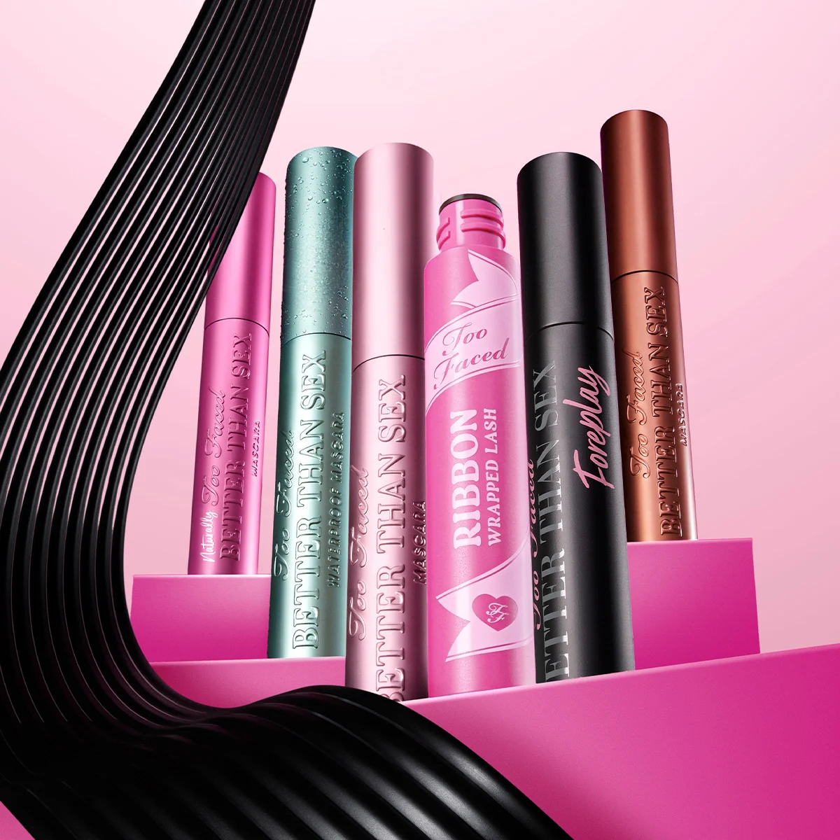 Kuusi eriväristä Too Faced -ripsiväriä vaaleanpunaisella taustalla. Vasemmalta oikealle: pinkki, vihreä, vaaleanpunainen, vaaleanpunainen nauhakuvioitu, musta ja pronssinvärinen.