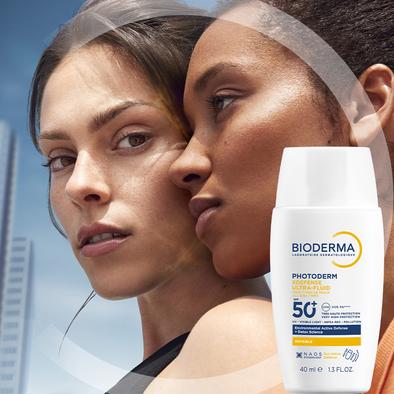 Närbild av två kvinnor som står nära varandra. I det högra hörnet visas en solkräm från Bioderma.