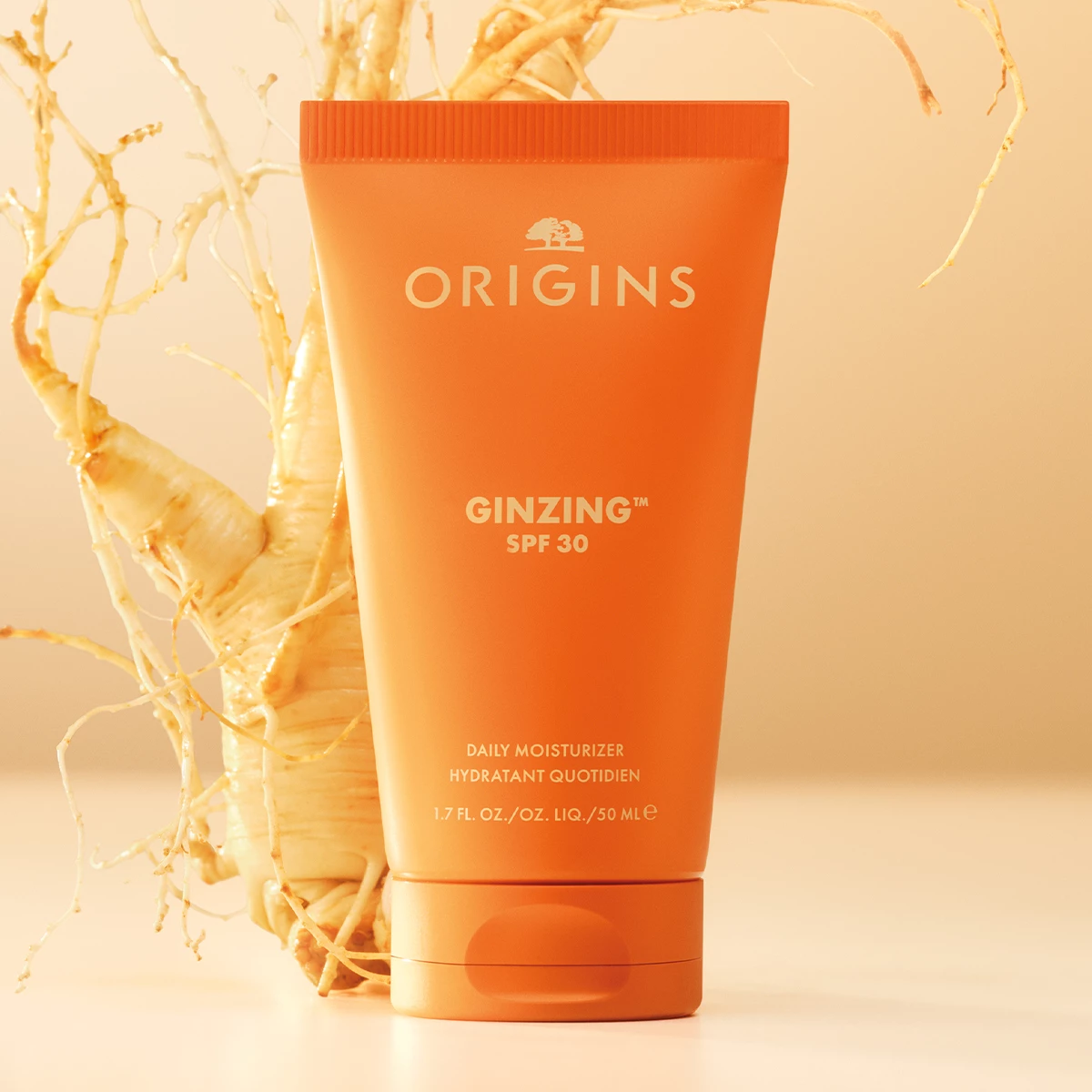 Origins GinZing SPF 30 Daily Moisturizer asetettuna ginsengjuuren eteen vaaleaa taustaa vasten.