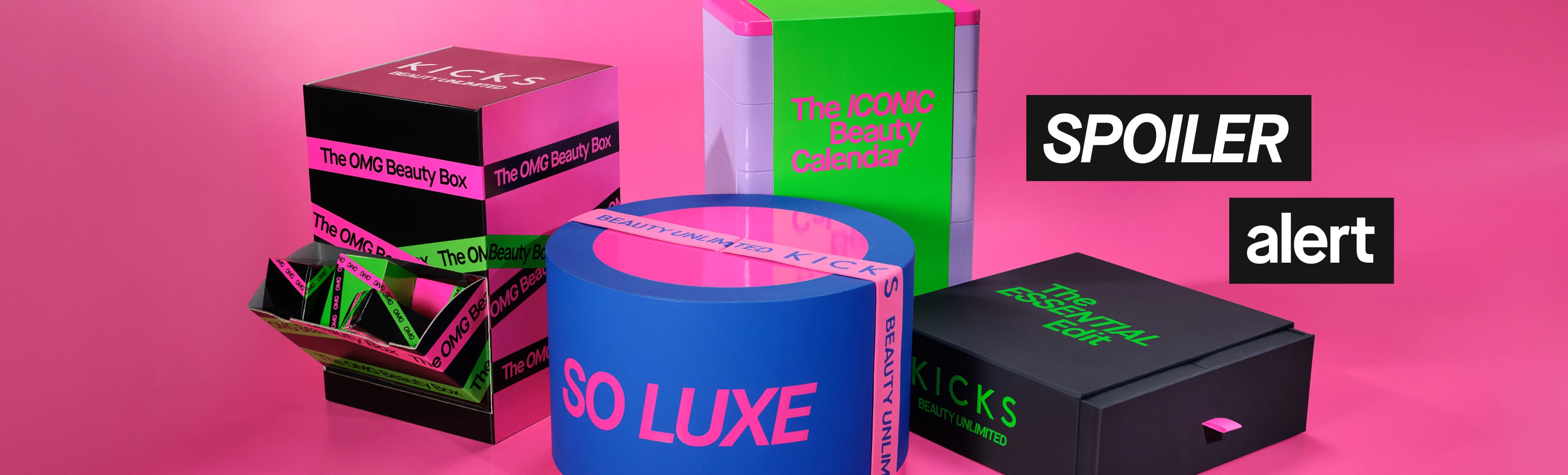 Teksti “SPOILER alert” näkyy värikkäiden KICKS-lahjapakkausten päällä vaaleanpunaisella taustalla. Pakkauksissa lukee “KICKS BEAUTY UNLIMITED”, “The OMG Beauty Box”, “The ICONIC Beauty Calendar”, “SO LUXE” ja “The ESSENTIAL Edit”.