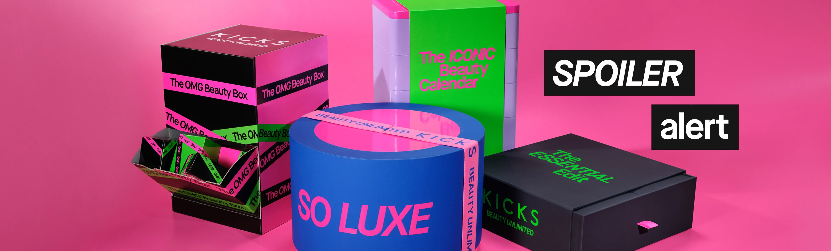 Teksti “SPOILER alert” näkyy värikkäiden KICKS-lahjapakkausten päällä vaaleanpunaisella taustalla. Pakkauksissa lukee “KICKS BEAUTY UNLIMITED”, “The OMG Beauty Box”, “The ICONIC Beauty Calendar”, “SO LUXE” ja “The ESSENTIAL Edit”.