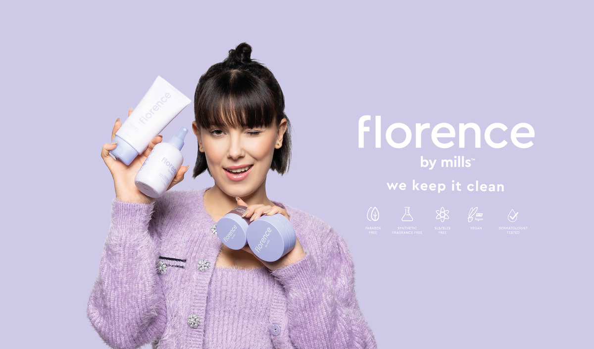 Violettiin neuletakkiin pukeutunut henkilö pitää kädessään useita Florence by Mills -merkin ihonhoitotuotteita. Tausta on vaalean violetti ja teksti ”florence by mills we keep it clean” on sijoitettu henkilön oikealle puolelle. Tekstin alapuolella on kuvakkeita, jotka osoittavat, että tuotteet eivät sisällä parabeeneja, synteettisiä hajusteita, SLS/SLES:ää, ovat vegaanisia ja dermatologisesti testattuja.