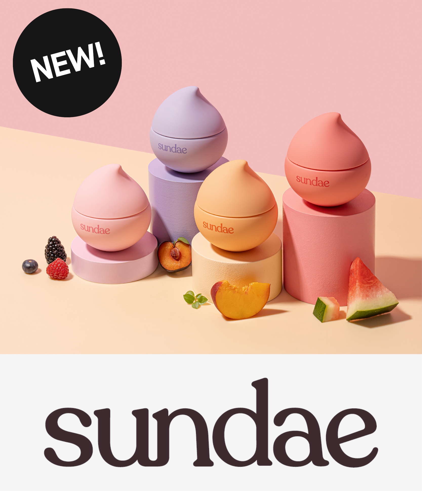 Sundae-merkin kolme pyöreää voidetta pastellisävyisissä purkeissa, esillä värikkäillä jalustoilla. Taustalla vaaleanpunainen ja persikanvärinen gradientti, ympärillä marjoja ja hedelmiä. Teksti 'NEW!' yläkulmassa.